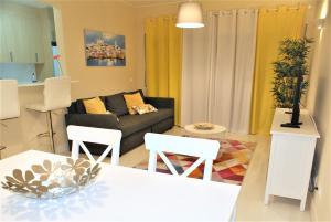 ein Wohnzimmer mit einem Sofa, einem Tisch und Stühlen in der Unterkunft Apartamento Litoral Mar 9 in Portimão