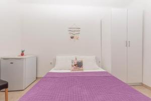 a purple bed in a room with white walls at Apartmani Sol in Makarska