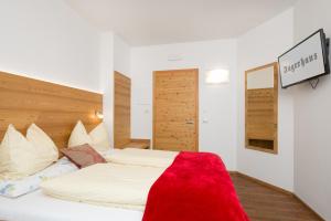 una camera da letto con un letto con una coperta rossa sopra di Jägerhaus a Pellizzano