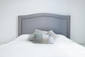 ein weißes Bett mit grauem Kopfteil und Kissen in der Unterkunft Poseidon Luxury Apartment in Karpathos