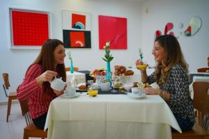 two women sitting at a table eating food at Piccadilly Rooms Restaurant and Beach in Santa Maria al Bagno