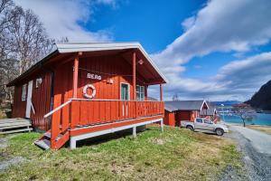 czerwony dom z samochodem zaparkowanym przed nim w obiekcie Skjervøy Lodge w mieście Skjervøy