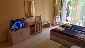 a room with a bedroom with a television and a desk at Harmony Hills Kolevi Apartments in Rogachevo