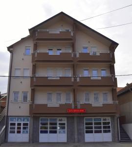 a tall building with a red sign in front of it at Apartmani Marić in Novi Pazar