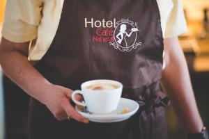 osoba trzymająca filiżankę kawy i talerz w obiekcie Hotel Café Nahetal - Hotel garni w mieście Gensingen