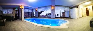 a large swimming pool in a building with a large window at Pensiunea Select Moeciu in Moieciu de Sus