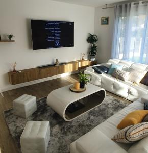 Il comprend un salon doté d'un canapé blanc et d'une télévision à écran plat. dans l'établissement Appartement Confortable, à Biguglia
