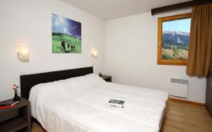 a hotel room with a bed and a painting on the wall at Résidence Le Chalet de L'Eterlou by Popinns in Saint-Chaffrey