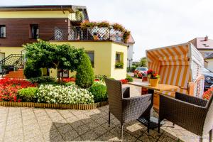 a patio with chairs and flowers in front of a building at Willa Oktawia in Niechorze