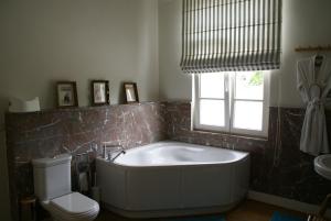 a bathroom with a tub and a toilet and a window at Au Coeur de la Famille in Knokke-Heist