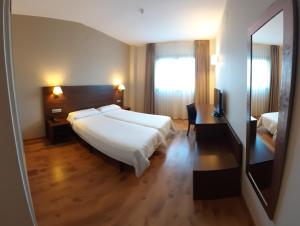 a bedroom with a bed and a desk and a mirror at Hotel Pago del Olivo in Simancas