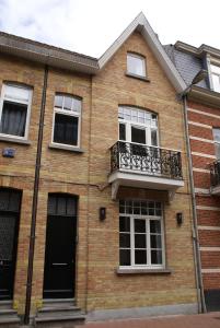 a brick house with a balcony and a door at Au Coeur de la Famille in Knokke-Heist