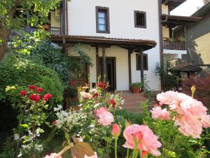 Oazis Guesthouse في Lovech: حديقة امام منزل به ورد وردي