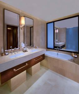 a bathroom with two sinks and a large mirror at Anantara Eastern Mangroves Abu Dhabi in Abu Dhabi