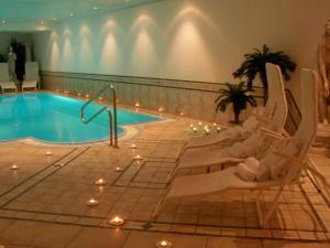 a swimming pool with chairs and lights in a building at Hotel Etschquelle in Resia