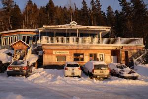 a house with cars parked in the snow at Auberge jeunesse Rose des Vents in Sainte-Rose-du-Nord