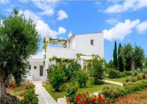 a white house with a garden in front of it at Masseria Montefieno in Castellana Grotte