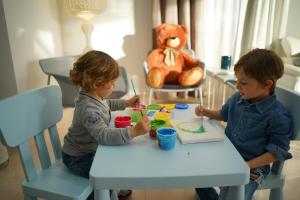 two children sitting at a table playing with paints at Piccadilly Rooms Restaurant and Beach in Santa Maria al Bagno
