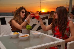 two women drinking wine at a table on a rooftop at Piccadilly Rooms Restaurant and Beach in Santa Maria al Bagno