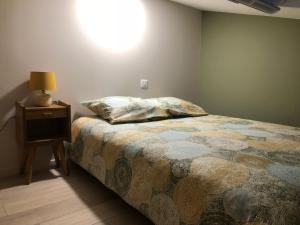 a bedroom with a bed and a lamp on a night stand at Duplex avec piscine in Villenave-dʼOrnon