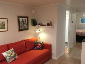 a living room with a red couch and a bedroom at Stuga i naturskönt område på västra Tjörn in Säby
