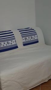 białe łóżko z białymi i niebieskimi poduszkami w obiekcie Casa Paola w mieście Favignana