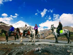 a group of people riding horses on a road at mariami in Kazbegi