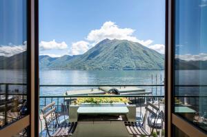 a balcony with a table and chairs and a view of a mountain at Hotel Argegno in Argegno