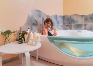 a woman sitting in a tub in a bathroom at Piccadilly Rooms Restaurant and Beach in Santa Maria al Bagno