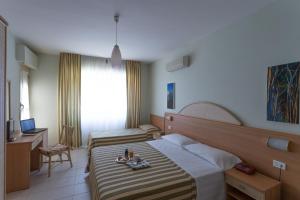 a hotel room with two beds and a desk at Hotel Jollino in Pineto