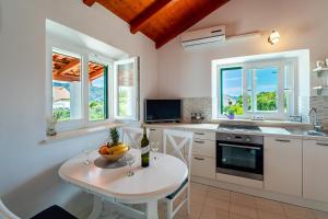 a kitchen with a table and some windows at Vineyard House & Olive Grove House in Račišće