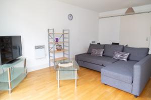 ein Wohnzimmer mit einem Sofa und einem TV in der Unterkunft Serviced Apartment In Liverpool City Centre - Free Parking - Balcony - by Happy Days in Liverpool