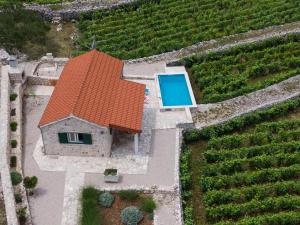 einen Blick über ein Haus mit einem orangenen Dach und einem Pool in der Unterkunft Vineyard House & Olive Grove House in Račišće