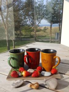 two coffee cups sitting on a table with strawberries at Golden Beach in Šventoji