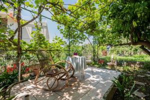 una mesa y sillas en un jardín bajo un árbol en Apartments Amalia, en Podgora