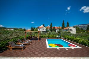 un patio trasero con piscina, sillas y una casa en Sunny House, en Korčula