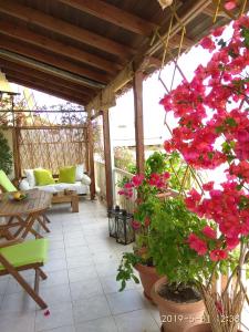 eine Terrasse mit roten Blumen, einem Tisch und Stühlen in der Unterkunft Romantic and cosy apartment in Athen