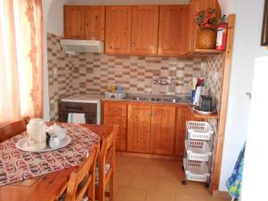 a kitchen with wooden cabinets and a table and a sink at Villas Michalis in Chorafakia
