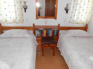 a bedroom with two beds and a chair and a book shelf at Villas Michalis in Chorafakia