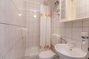 a white bathroom with a toilet and a sink at Apartments Amalia in Podgora +20 photos