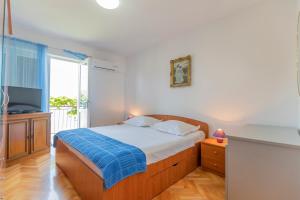 a bedroom with a bed and a tv and a window at Apartments Amalia in Podgora
