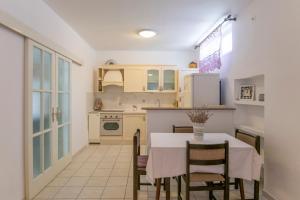 a kitchen with a table and chairs and a kitchen with white cabinets at Apartments Amalia in Podgora