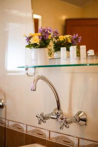 a bathroom sink with a glass shelf with flowers on it at Hotel Albatros Old Town in Sozopol