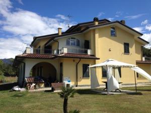 een groot geel huis met een paraplu in de tuin bij Villa Naclerio in Sarzana