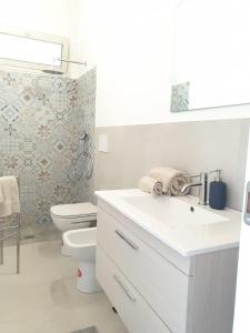 bagno bianco con servizi igienici e lavandino di A(m)mare - casa vacanze a Donnalucata