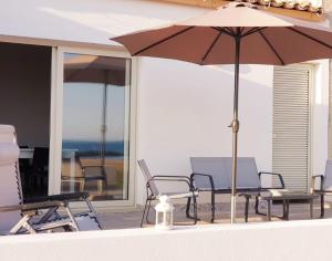 un tavolo con sedie e un ombrellone su un patio di A(m)mare - casa vacanze a Donnalucata