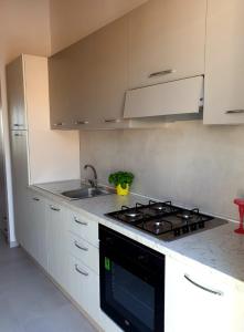 una cucina con armadi bianchi e piano cottura di A(m)mare - casa vacanze a Donnalucata