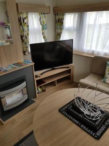 a living room with a fireplace and a flat screen tv at Delta Santana in Looe
