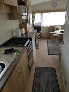 a kitchen with a stove and a living room at Delta Santana in Looe