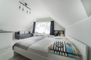 ヤスタルニャにあるNiebieska Willaの白いベッドルーム(ベッド1台、ソファ付)